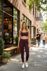 Aurum Activewear model wearing deep burgundy high-waisted full-length leggings and matching sports bra on city street